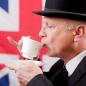 Preview: Ein Engländer mit Melone der eine Tasse Tee trinkt vor der Flagge Union Jack im Hintergrund