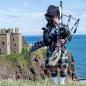 Preview: Ein Schotte mit Trachtenkleidung und Duddelsack eine Burg Meer und Himmel im Hintergrund