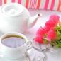Mobile Preview: Weiße Teetasse und weiße Teekanne mit rosa Blumen auf weißer Tischdecke im Hintergrund