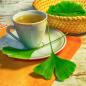 Mobile Preview: Teetasse mit Tee und Ginkgoblätterdavor und dahinter im Korb heller rustikaler Hintergrund Hintergrund