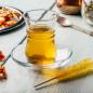 Preview: Apfeltee im türkischen Glas mit Kandis Stick und Löffel auf einem Tisch heller rustikaler Hintergrund