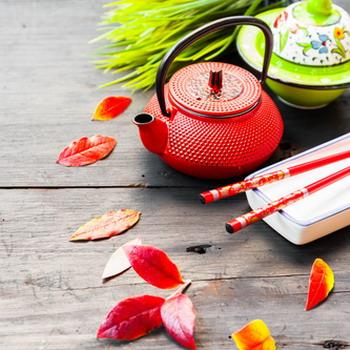 Rote Eisen Kanne mit roren Blättern davor rustikale Tischplatte rustikaler Hintergrund