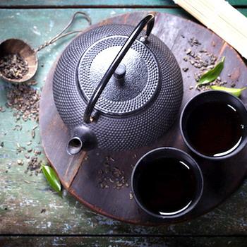 Alte Teekanne mit 2 Teeschalen und Teesieb rustikaler Hintergrund