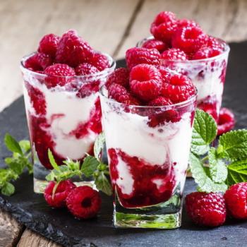 Drei Desserts mit Himbeeren Sahne Cream auf einem rustikalen Tisch  Decke im Hintergrund