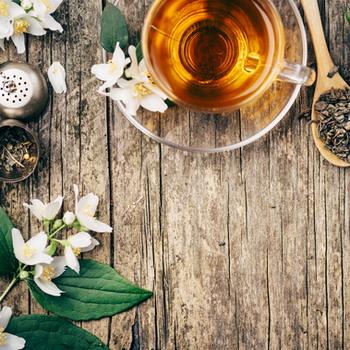 Jasminblüten mit einer Tasse grünen Tee auf rustikalen Hintergrund