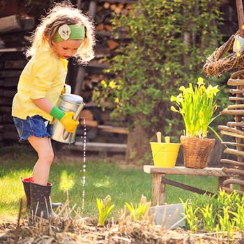 Kind beim gießen von Pflanzen in Omas Garten rustikaler Hintergrund