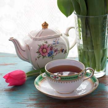 Teetasse und Teekanne mit einer Tulpe auf ein rustikalen Tisch und weißer Hintergrund