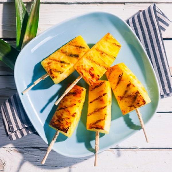 Ananas am Stiel auf einem hellblauen Teller im Hintergrund