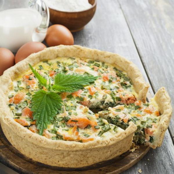 Frisch gebackener Brennessel Quiche mit Eier Milch und Mehl auf rustikalen Hintergrund