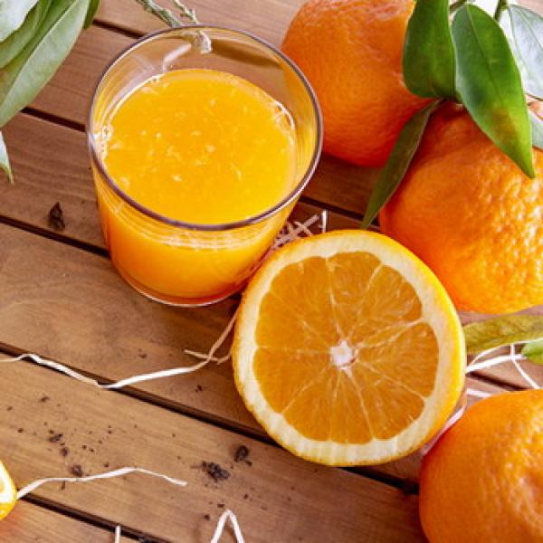 Saftige Orangen mit frisch gepressten Orangensaft rustikaler Hintergrund