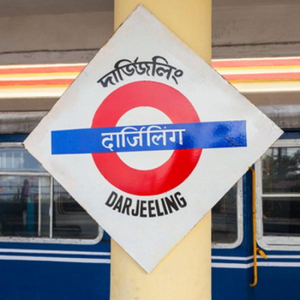 Bahnhofschild mit Darjeeling als Aufschrift mit blauen Zug als Haltestelle   Hintergrund