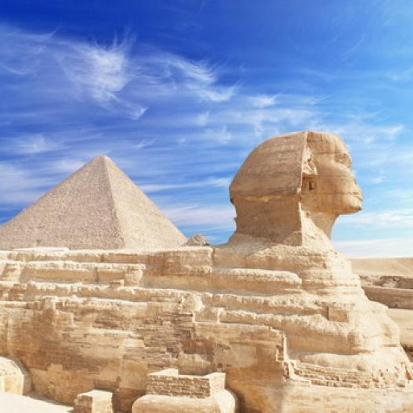 Sphinx im Vordergrund und ein Pyramide im Hintergrund plus blauer Himmel