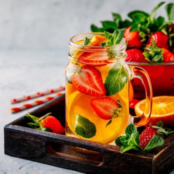 Glasbecher mit frisch aufgeschnittene Erdbeeren und Orangen rustikaler weißer Hintergrund