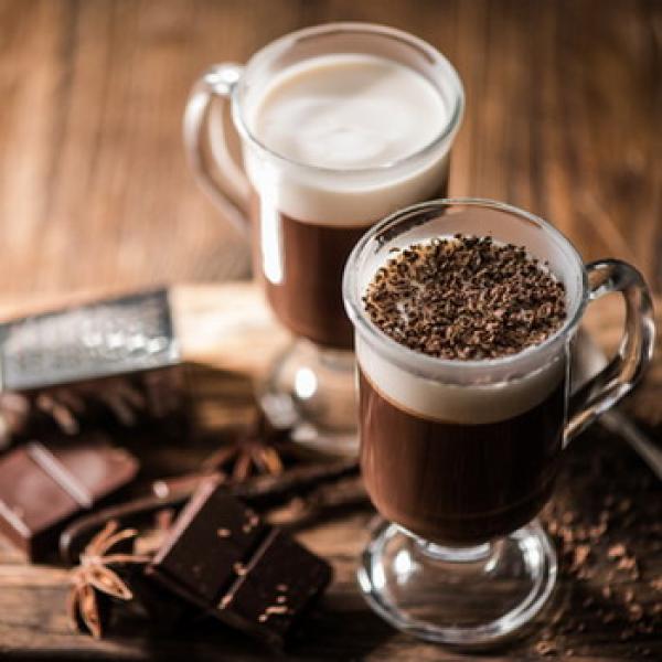 2 Irish Coffee mit Schokolade im Vordergrund und eine Holzplatte im Hintergrund