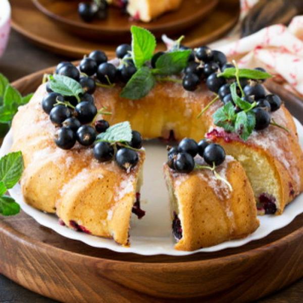 Kuchen mit schwarzen Johannisbeeren mit Holzteller auf einem Tisch Hintergrund