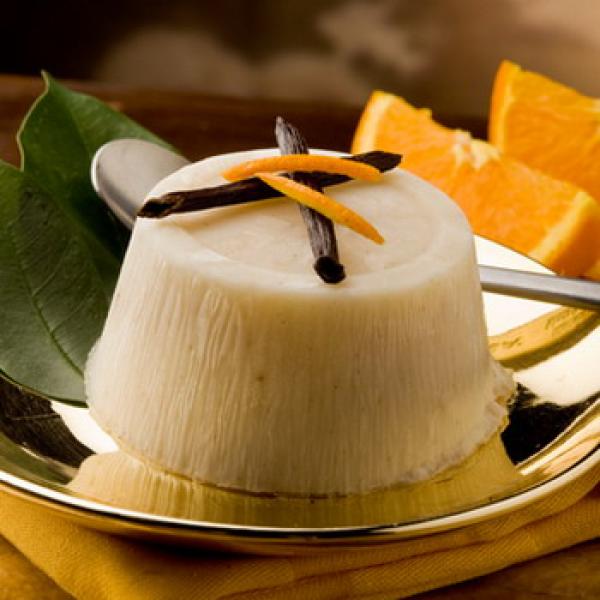 Dessert mit Vanille auf einem goldenem Teller mit Orangen im Hintergrund